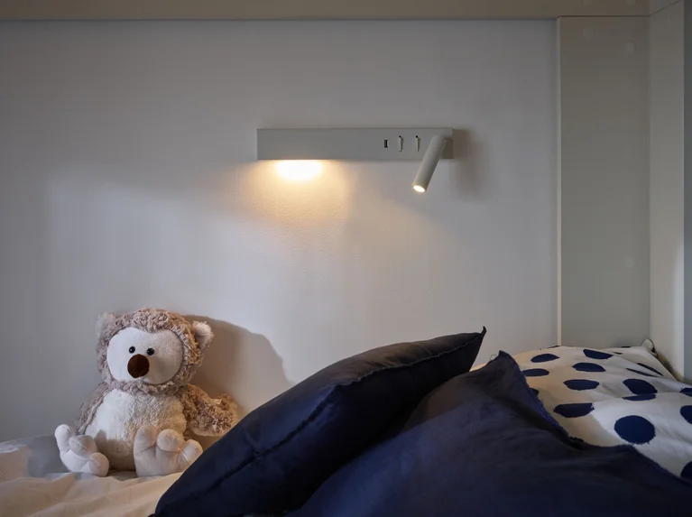 Lampka na ścianie zawieszona przy łóżku piętrowym 